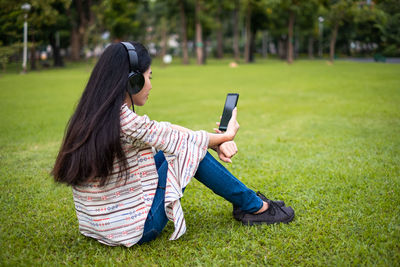 Full length of teenage girl using mobile phone in park