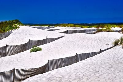 Snow covered land against clear blue sky