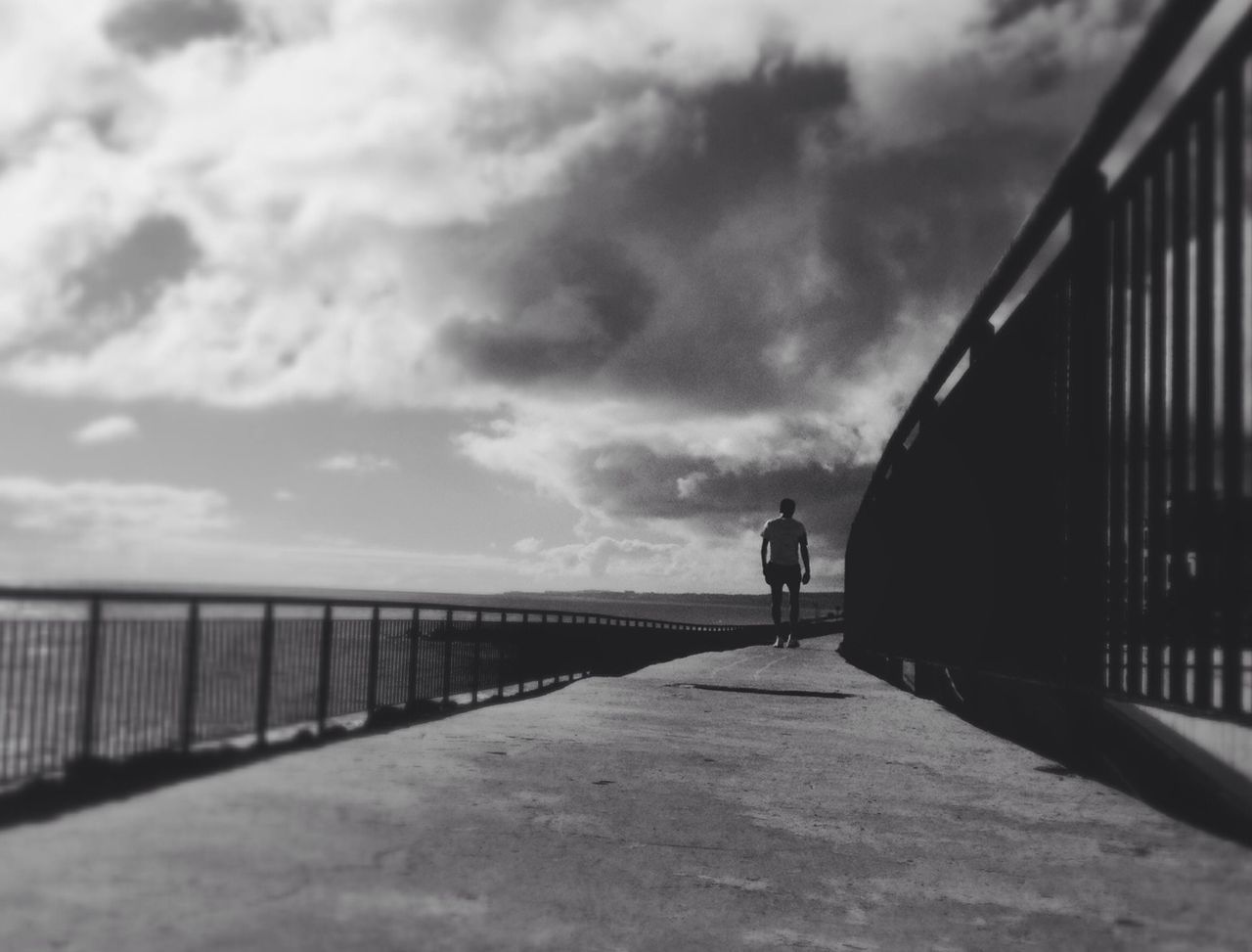 sky, cloud - sky, railing, the way forward, built structure, architecture, cloudy, rear view, lifestyles, cloud, walking, men, sea, diminishing perspective, full length, leisure activity, weather, vanishing point