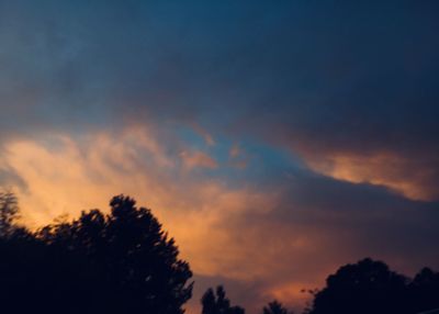 Low angle view of silhouette trees against dramatic sky