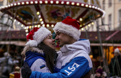 Portrait of young couple with carousel in amusement park