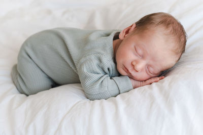 Cute newborn baby boy sleeping on bed at home