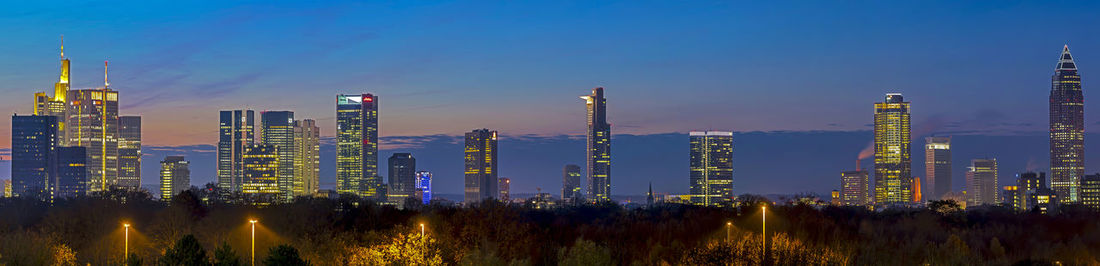 Panoramic view of illuminated cityscape against clear blue sky