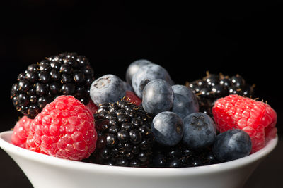 Close-up of strawberries in bowl on table against black background