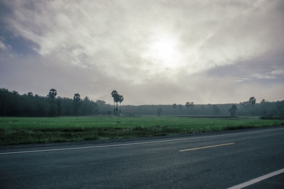 Road by field against sky