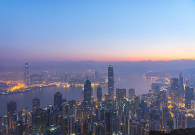 High angle view of river amidst illuminated city at dusk