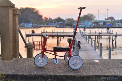 Toy bicycle at waterfront, wooden boardwalk and sunset background