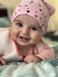 Portrait of cute baby smiling girl lying on bed