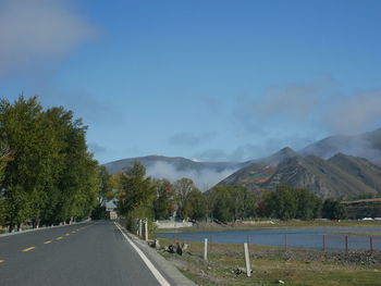 Road by trees against sky