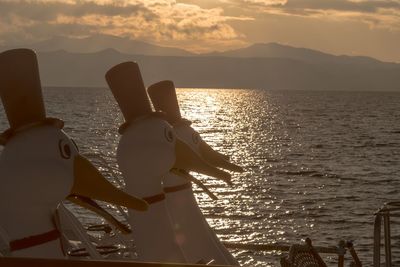 Rear view of people sailing on sea against sky during sunset