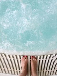 Low section of woman standing in swimming pool