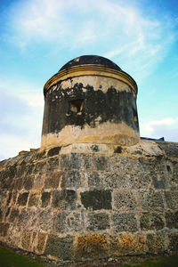 Low angle view of old building against cloudy sky