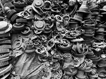 Pile of used machine parts are oily and rusty in second hand machinery shop, black and white