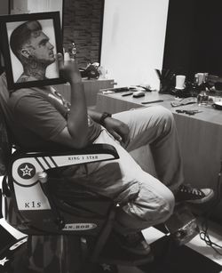 Rear view of man smoking cigarette while sitting on table