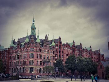 Buildings in town against cloudy sky