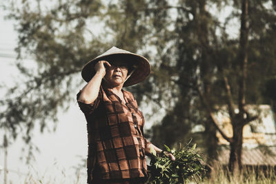 Portrait of smiling woman standing against plants