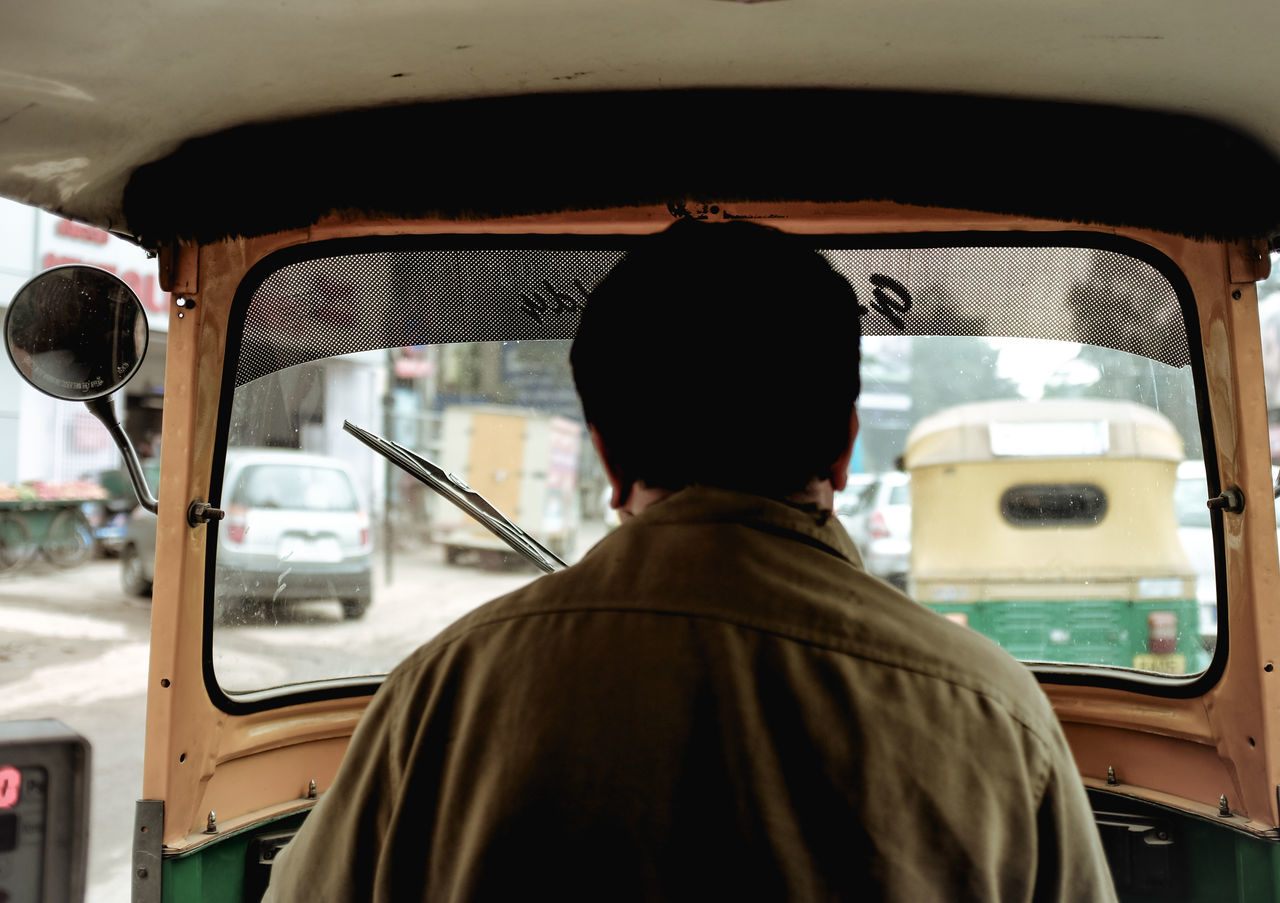 REAR VIEW OF MAN TRAVELING IN BUS