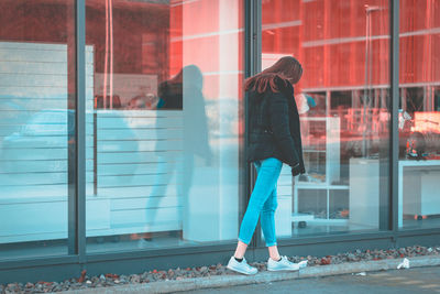 Rear view of woman standing against window