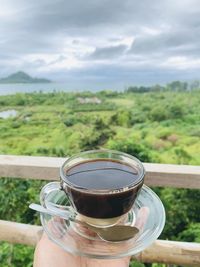 Cropped image of person holding coffee cup against sky