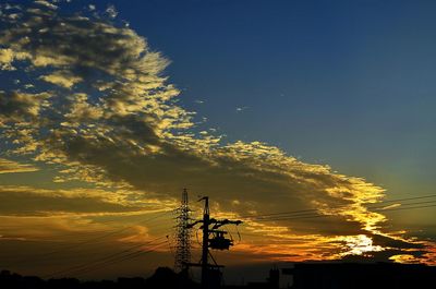 Low angle view of silhouette electricity pylon against sky during sunset