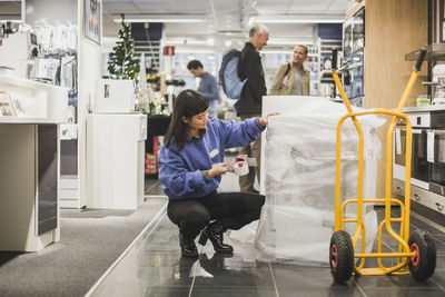 Saleswoman packing while customers looking for appliances in store