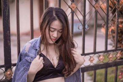 Young woman wearing hat standing against fence