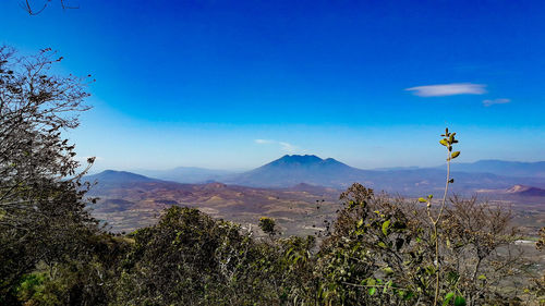 Scenic view of mountains against blue sky