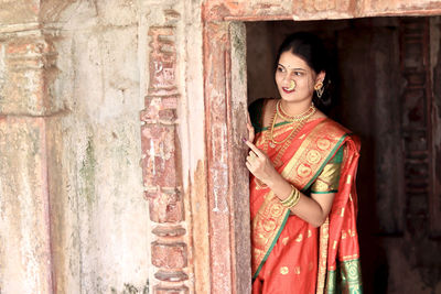 Portrait of young woman standing against old building