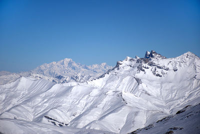 Snowcapped mountains against clear blue sky
