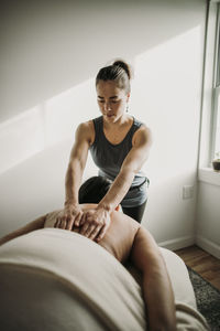 Female massage therapist places her hands on her patient's back