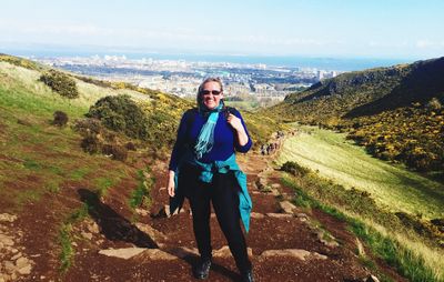 Portrait of smiling woman standing on landscape against sky