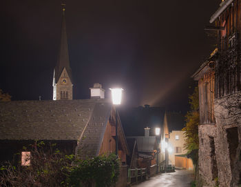 Illuminated street amidst buildings at night