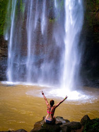 Full length of woman standing against waterfall