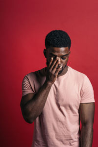 Portrait of man standing against red background