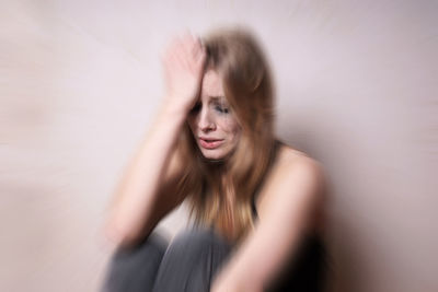 Blurred motion image of crying woman against wall