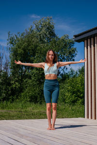 Full length of young woman standing on footpath against sky