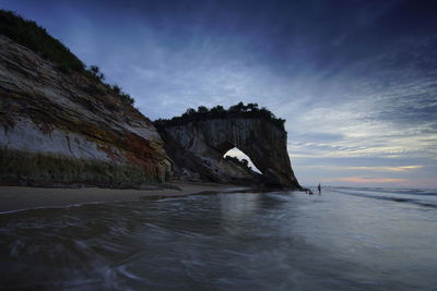 Rock formations on shore against sky during sunset