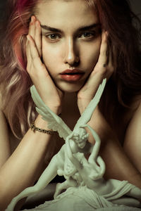 Portrait of naked woman with sculpture lying on bed