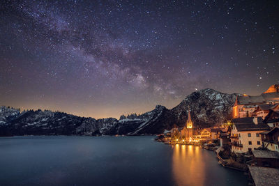 Scenic view of lake by mountains against milky way at night