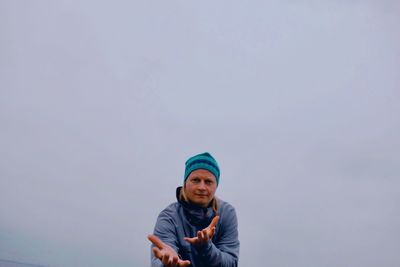 Portrait of man gesturing against sky