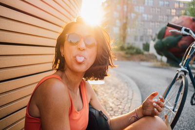 Portrait of woman sticking out tongue while sitting outdoors