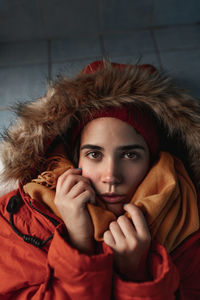 Young contemplative ethnic female in trendy knitted hat and scarf looking away on blurred background