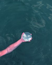 Close-up of person holding mirror in lake