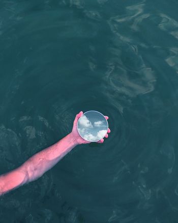 Close-up of person holding mirror in lake