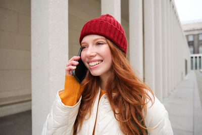 Young woman standing against wall