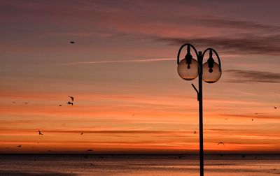 Silhouette beach against sky during sunset