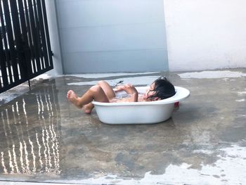 Boy lying down in bathtub