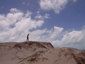 Man standing on sand dune at desert against sky