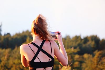 Rear view of woman standing against clear sky