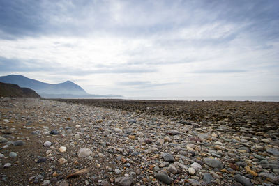 Surface level of stones on shore against sky